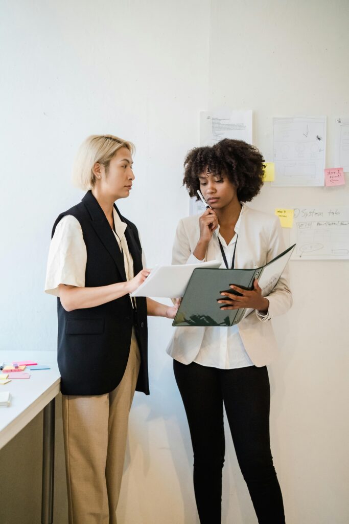 Two professionals reviewing project documents in front of planning notes